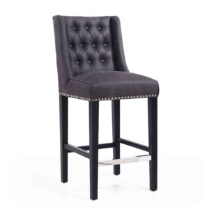 A dark gray, button-tufted barstool with a studded trim, featuring black legs and a metal footrest. The style is elegant and modern.