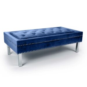 A plush, rectangular blue velvet ottoman with silver studs on the sides and sleek metal legs. It conveys a modern and luxurious style.
