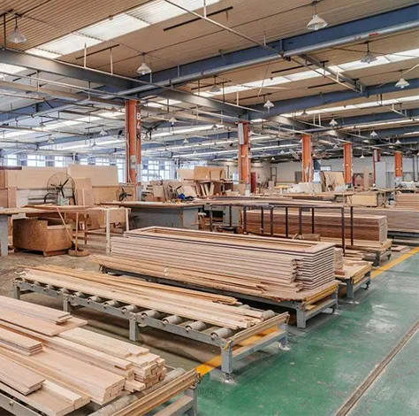 Wide view of a spacious, well-lit woodworking factory with stacks of wooden planks and workbenches, conveying a sense of industrious activity.