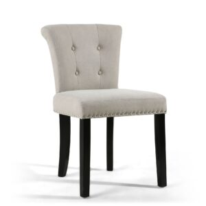 A beige upholstered chair with a slightly curved backrest featuring button tufting and silver studs along the edge. The chair has dark wooden legs.