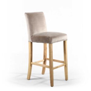 A beige velvet bar stool with a soft seat and backrest, supported by light wood legs and a footrest, placed against a plain white background.